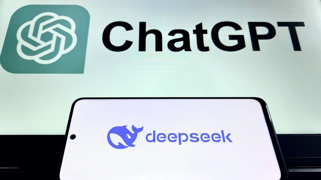 Mobile phone with Deepseek logo on the screen in front of the monitor displaying the chatgpt logo